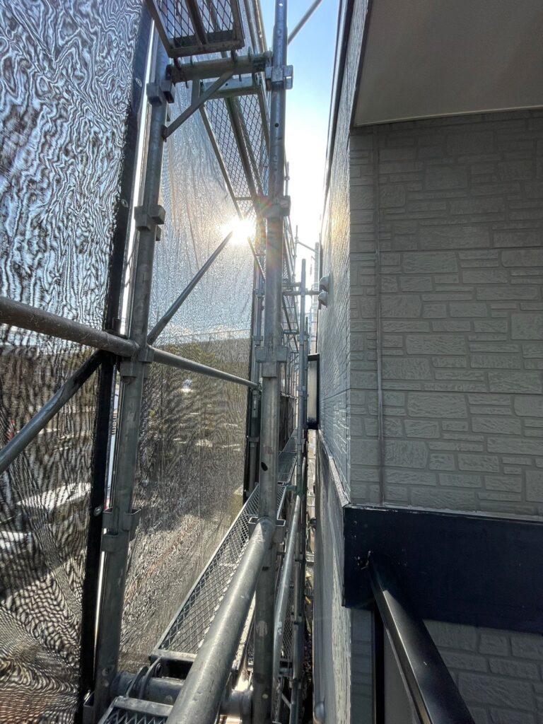建物まわりの足場支柱に安全用の養生材が取り付けられている様子